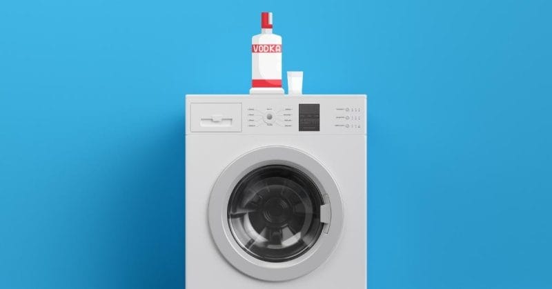 washing machine with bottle of vodka on top with blue background